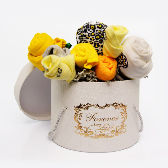 Μία κίτρινη σύνθεση όπου είναι ένα κουτί, μέσα στο οποίο βρίσκονται τοποθετημένα σε σχήμα λουλουδιών, σελτεδακια, φορμακια, κάλτσες και σαλιαρες.